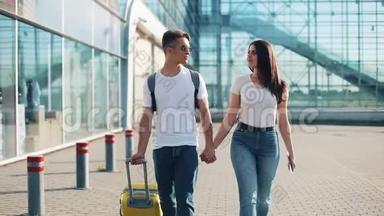 幸福的年轻夫妇带着行李去机场或火车站附近。 旅游、度假、度假的概念